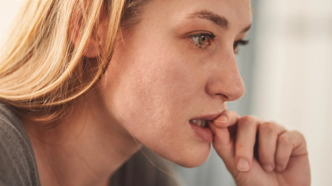 Körömrágás ellen küzdő fiatal szőke nő