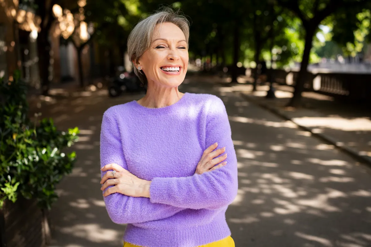 A tavaszi divat szerint öltözködő nő lila pulóvert visel.