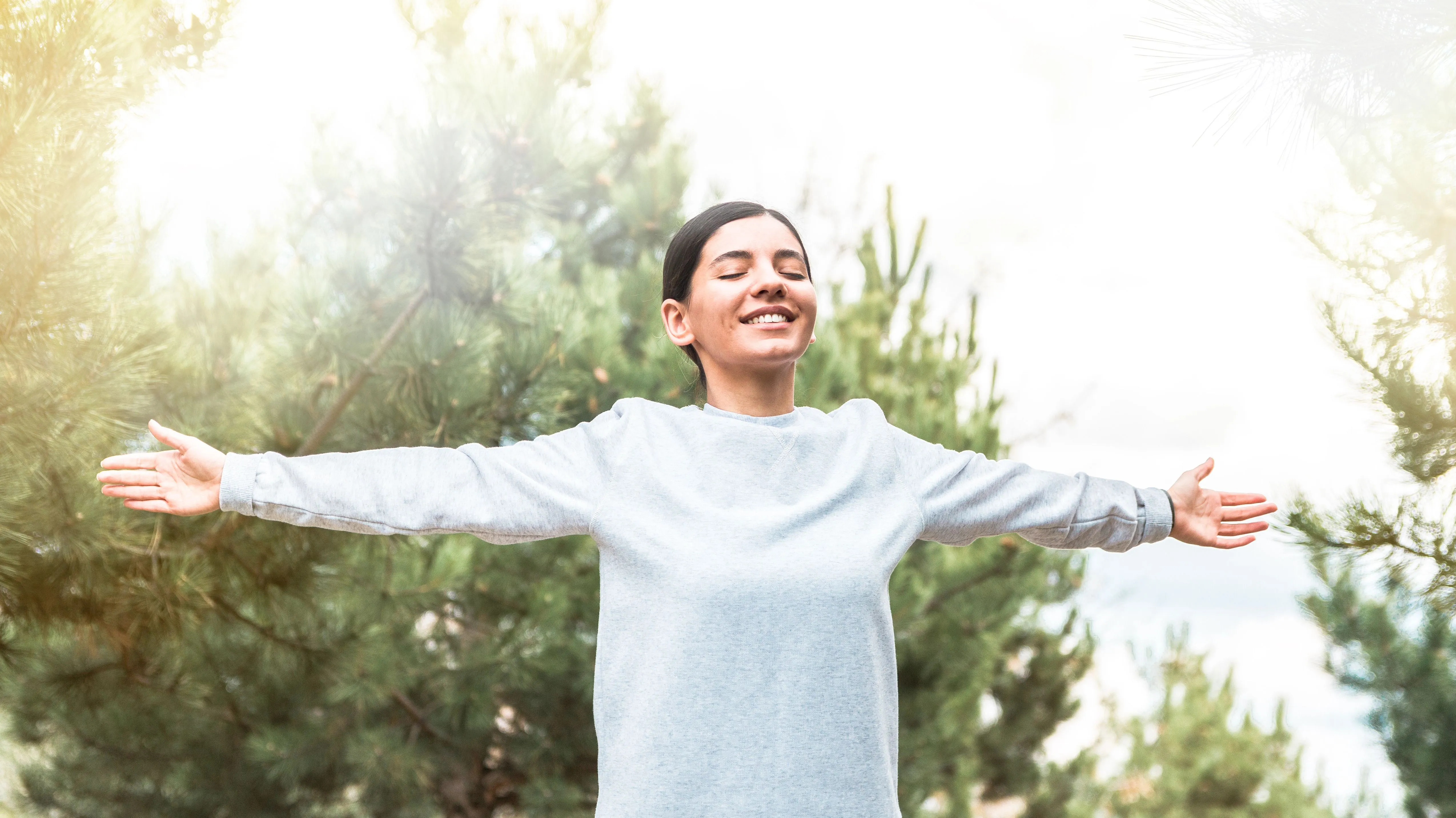 Személyiségtesztben szereplő kép egy karjait a szabadban kitáró mosolygó nőről