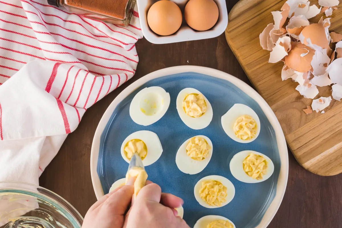 Diétás kaszinótojás recept alapján tölti a főtt tojásokat egy nő.