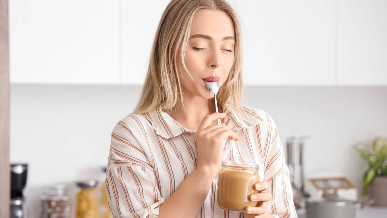 Konyhában poharas édességet kanalozó fiatal nő, aki cukor helyett fűszerekkel édesítette a desszertet