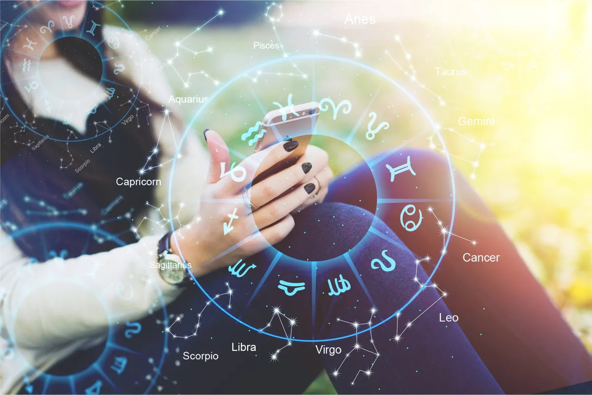 Egy telefonját néző nő a horoszkópban használt zodiákus kör mögött.