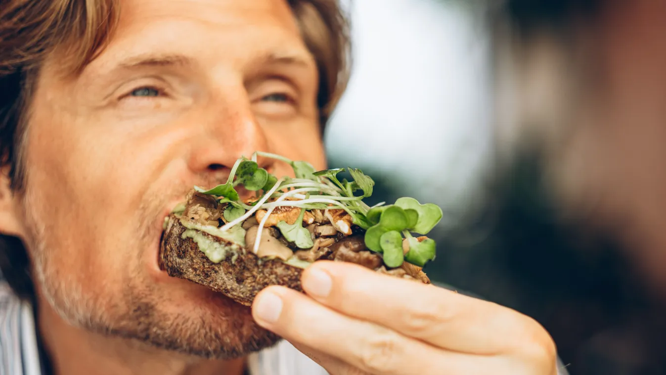 Diétás ételt fogyasztó férfi, aki teljes kiőrlésű kenyeret és salátát eszik.