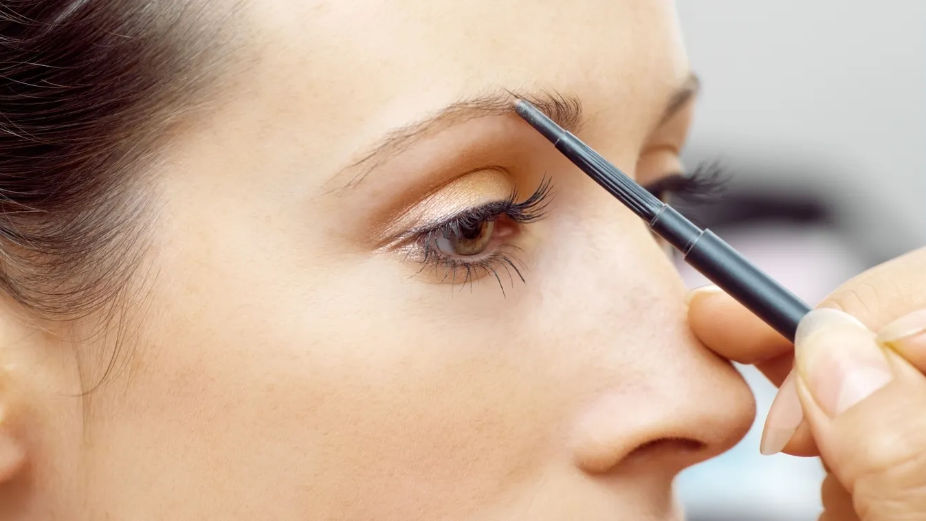 Sminkelő nő, aki szemöldökceruzát használ.