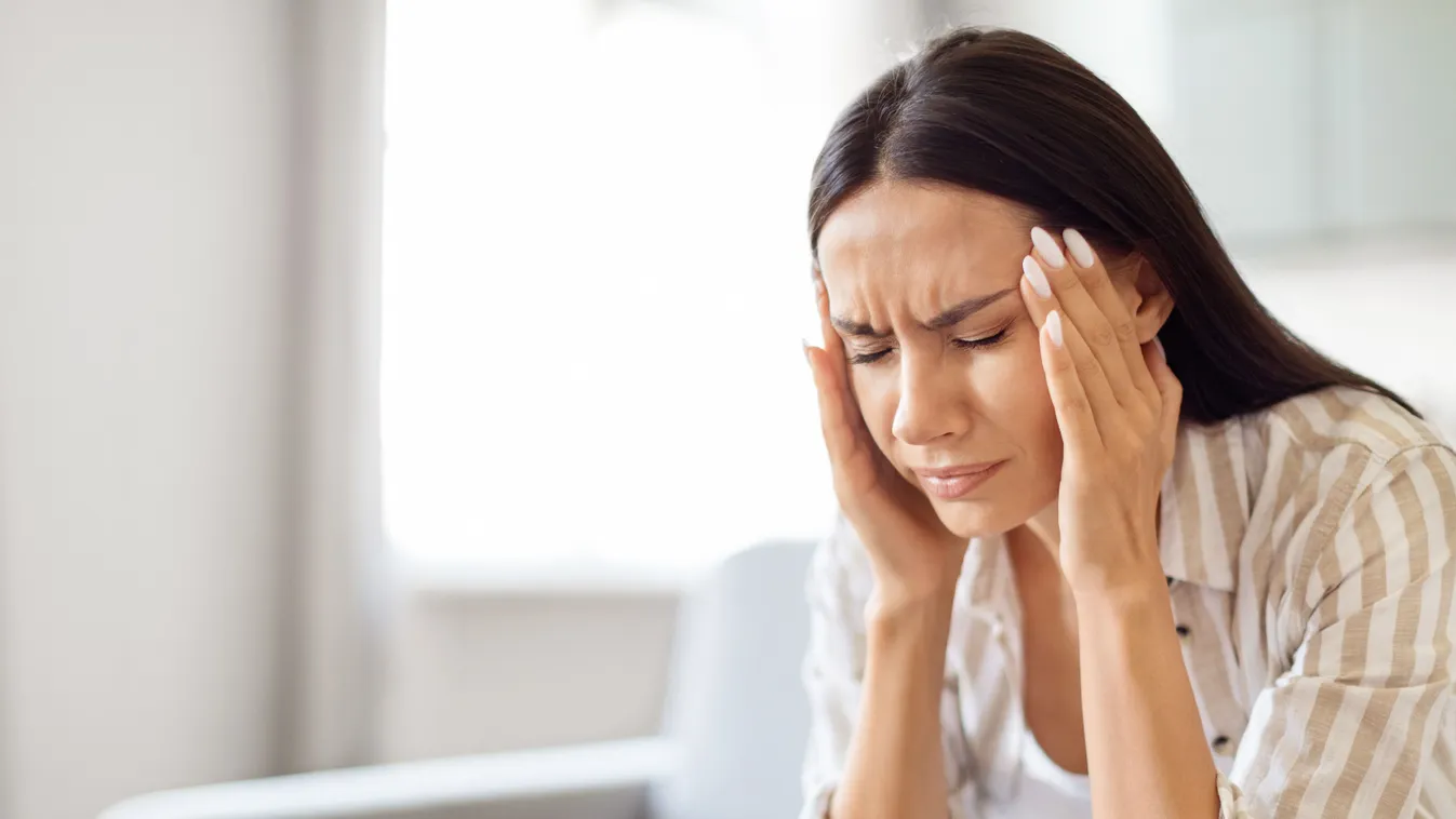 A fejét fogó nő, akinek migrénje van.