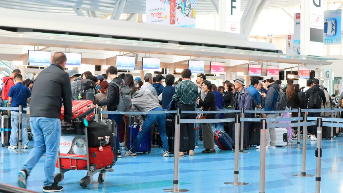 Új utazási trendek szerint utazó turisták a repülőtéri check-in pultoknál sorban állva