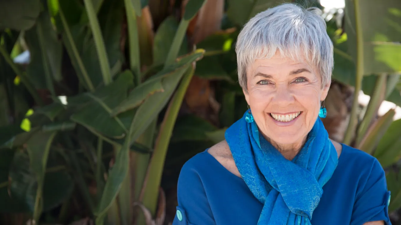 Kék felsőt és sálat viselő 50 feletti nő.