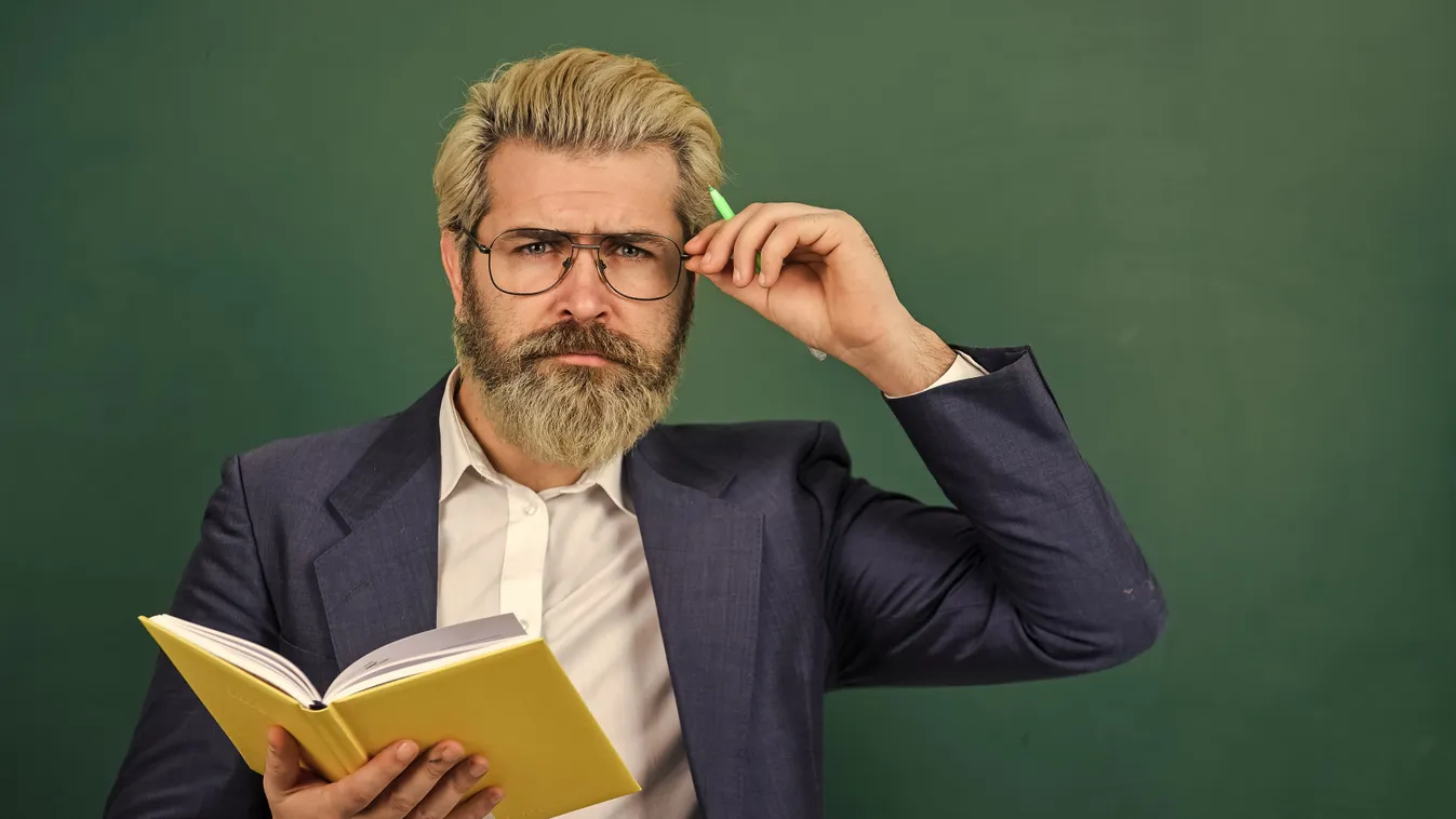 Történelm ikvízen gondolkodó szakállas férfi tanár.
