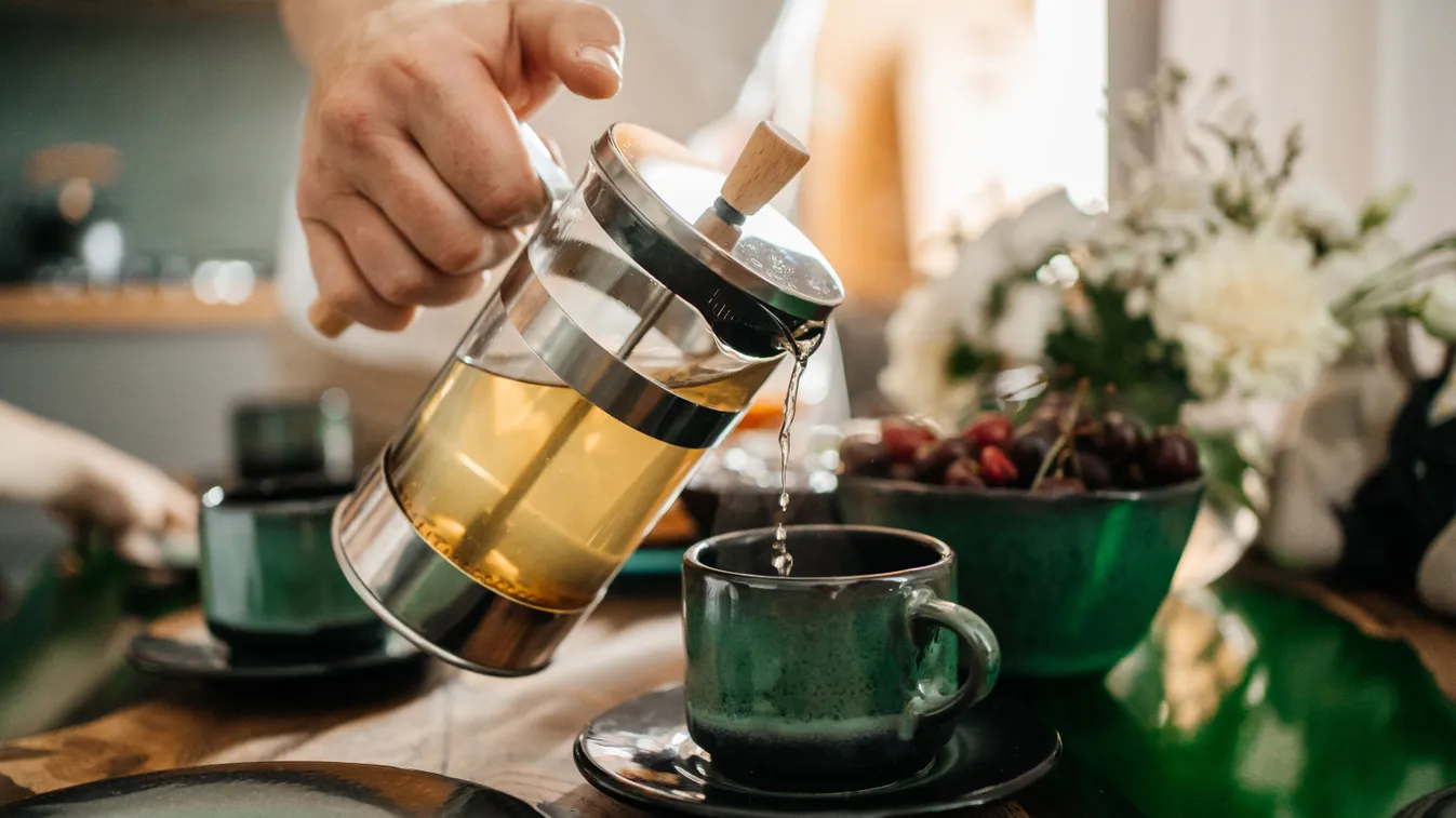 Egy férfi, aki odafigyel a gyakori teafogyasztásra és tölt magának az italból.