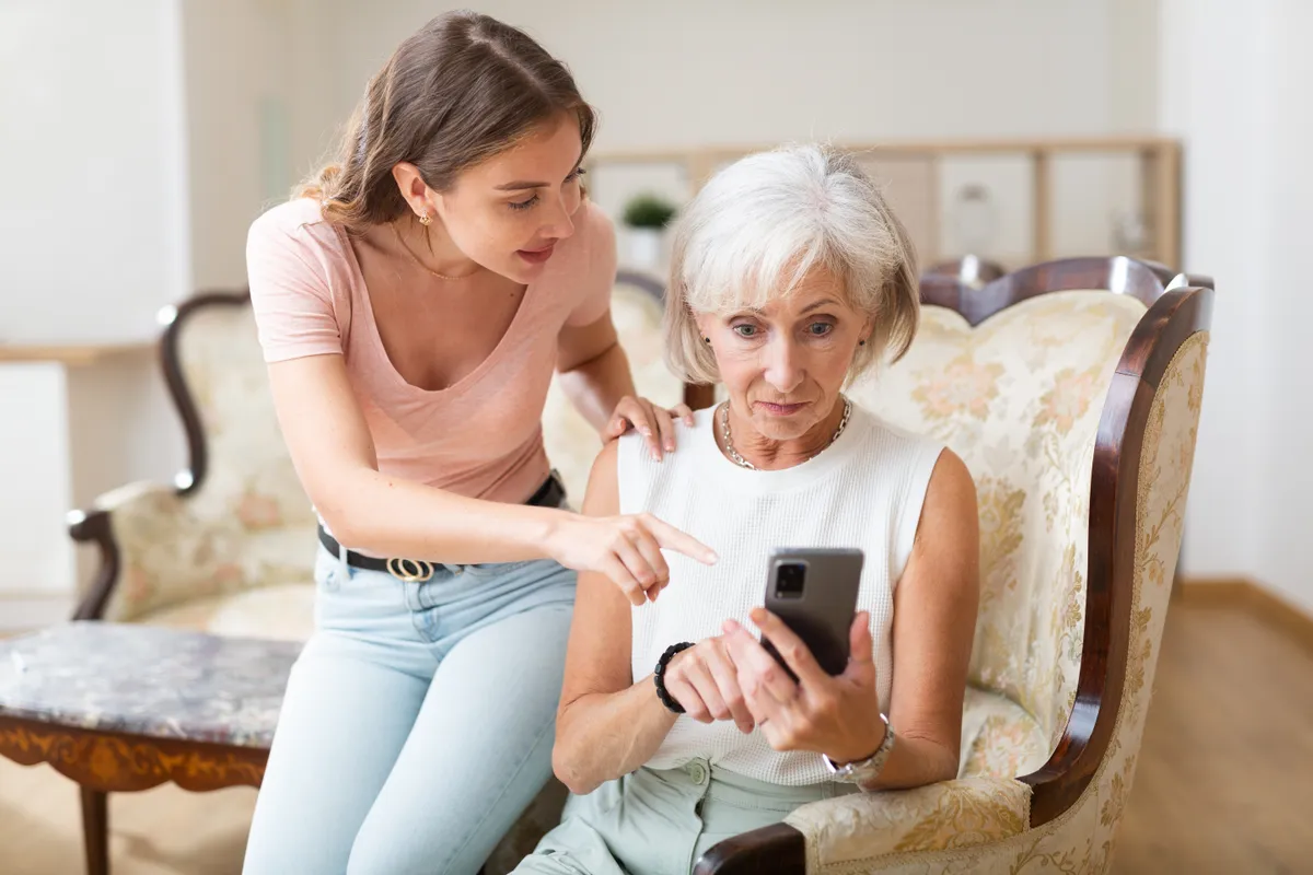 Idős asszony segítése egy okostelefonon elvégezhető kvíz kitöltésében