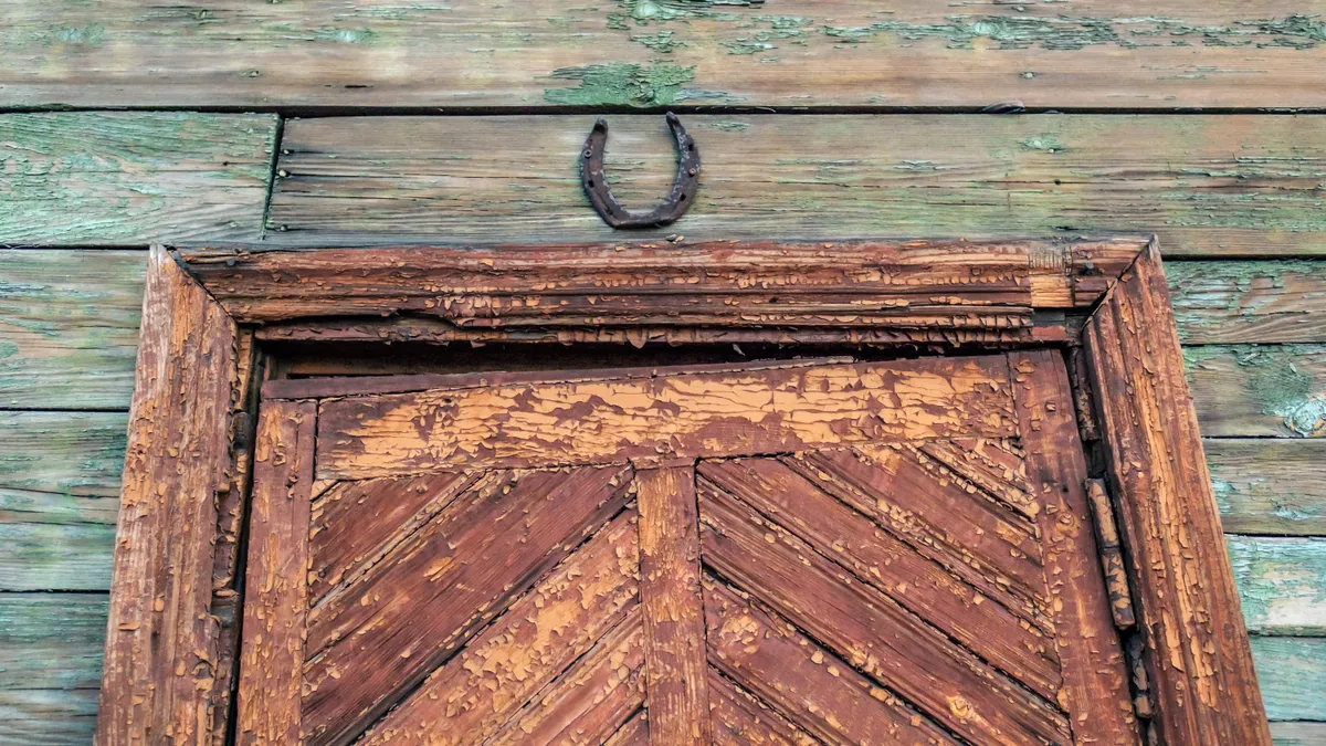 Mágikus védelemként és szerencsehozó szimbólumként felfelé fordított patkó egy ajtó fölött 