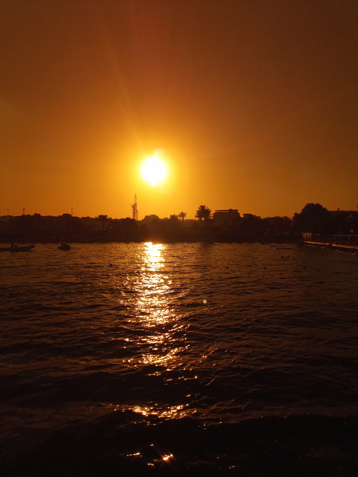 Naplemente a tengeren, háttérben a part sziluettje.