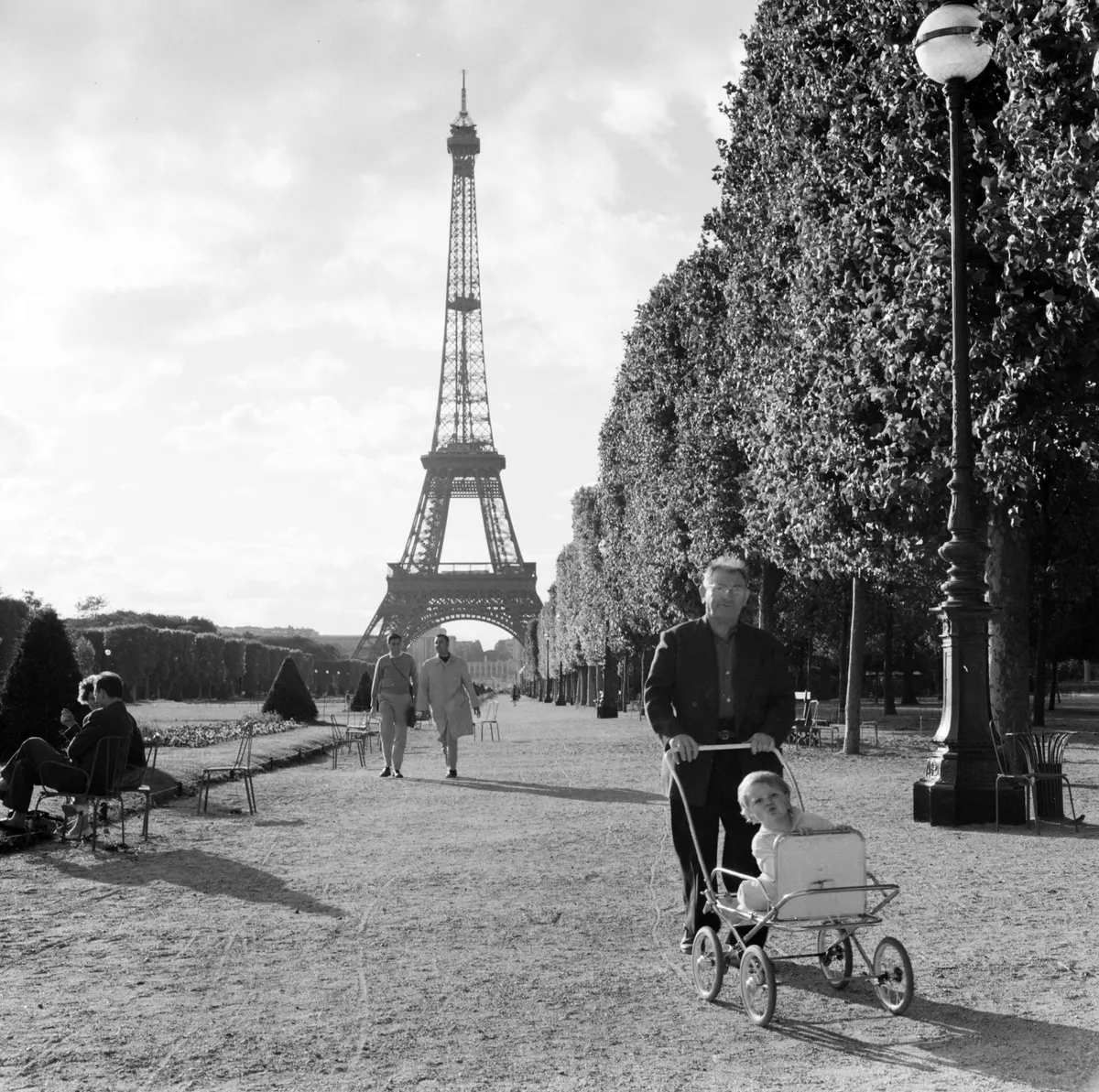 Apuka babakocsit tol a párizsi Mars-mezőn, háttérben az Eiffel-toronnyal, 1958.