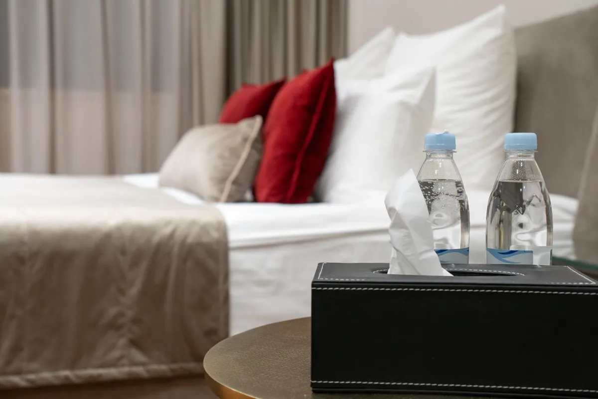 Szállodai szoba ágya vizespalackkal, ami egy szállodai trükk kelléke.
