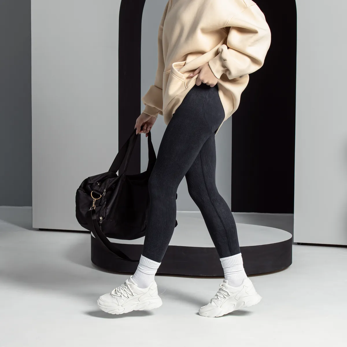 Egy fekete leggings nadrágot viselő nő táskával és fehér sportcipővel, a leggings veszélyes repülés közben.