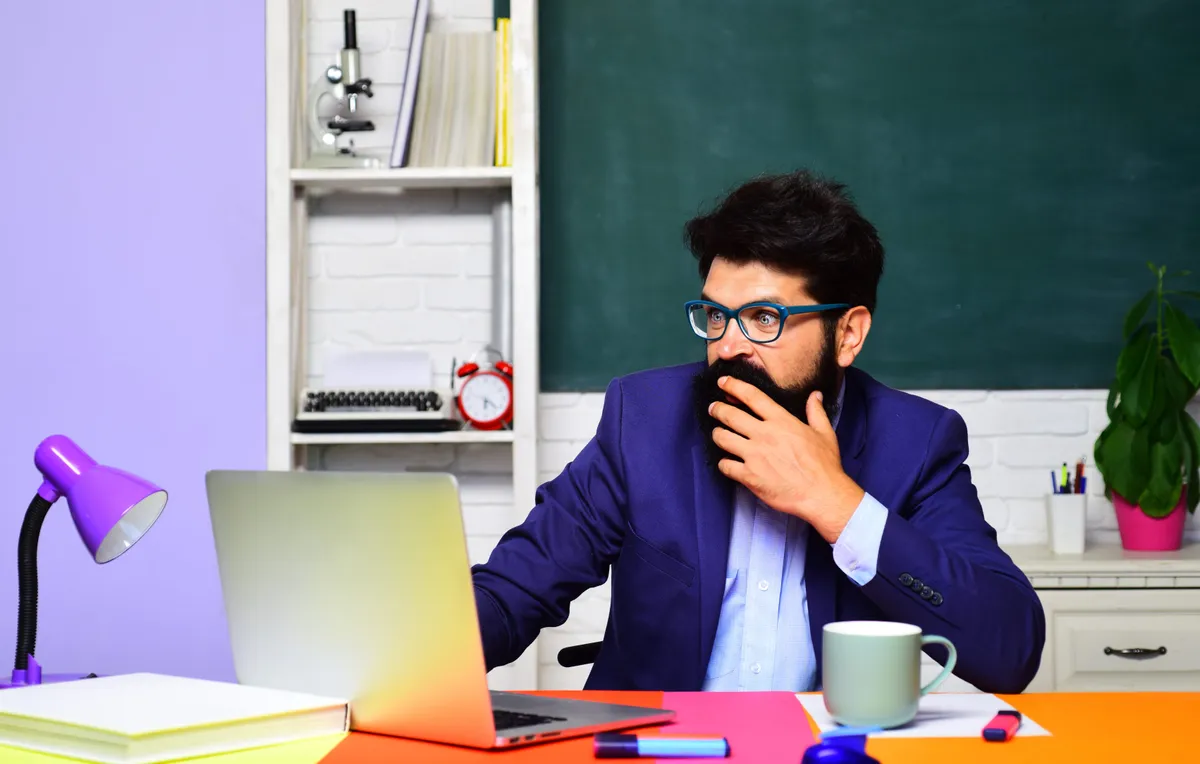 Szemüveges férfi egy műveltségi kvízt próbál kitölteni a laptopján.