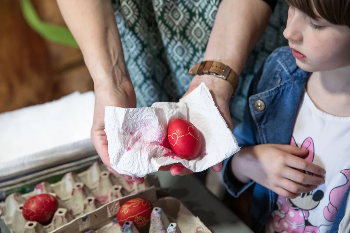 Tojásfestés után az anyuka mutatja a piros tojást a kislányának.
