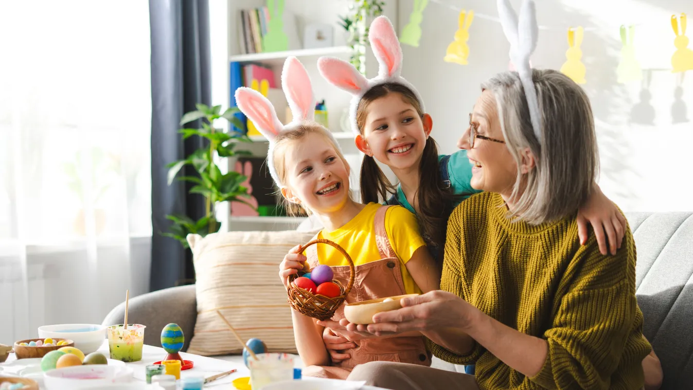 Húsvéti toásokat festő nagymama az unookáival a húsvéti kvízben.