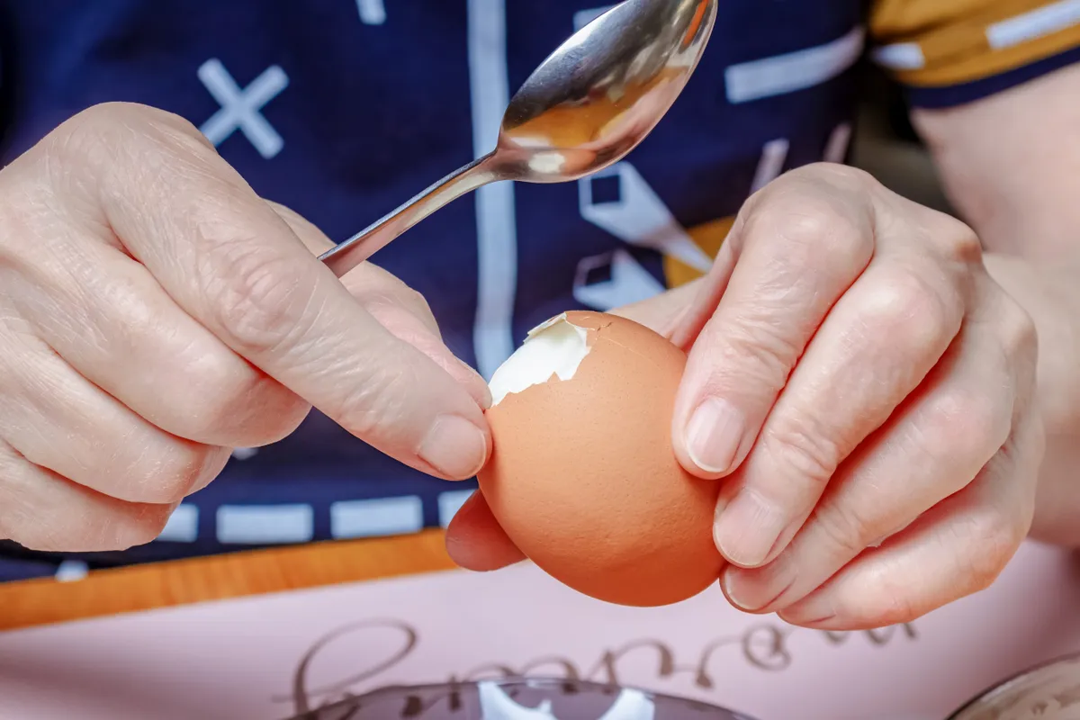 Tojásfőzés helyesen - férfi kézben főtt tojás pucolás közben.