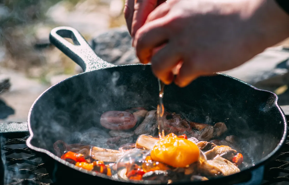 Saksuka készítése öntöttvas serpenyőben szabad tüzön, miután megtörtént a vasedény kezelése