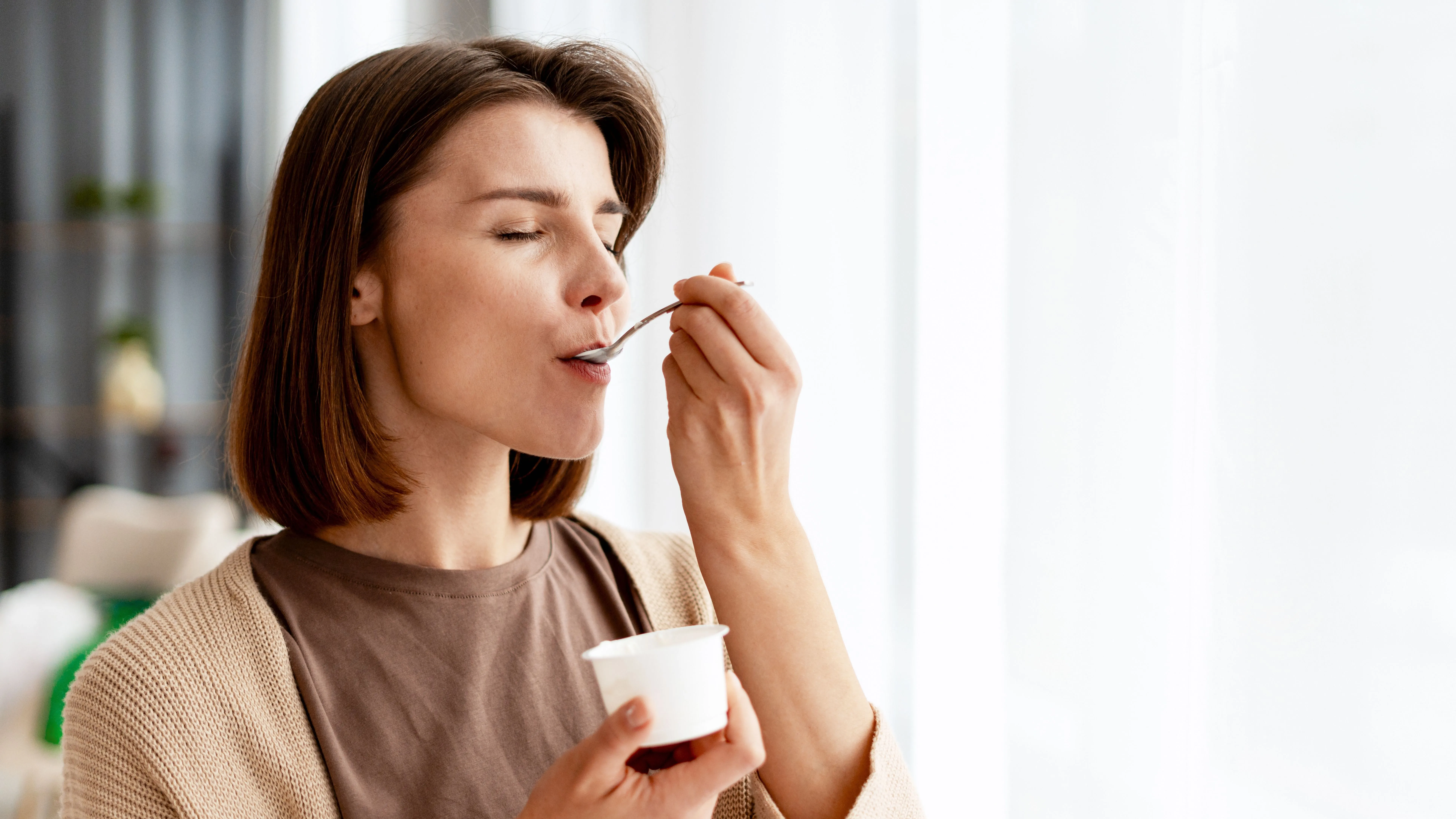 Gyulladáscsökkentő ételeket fogyasztó nő joghurtevés közben