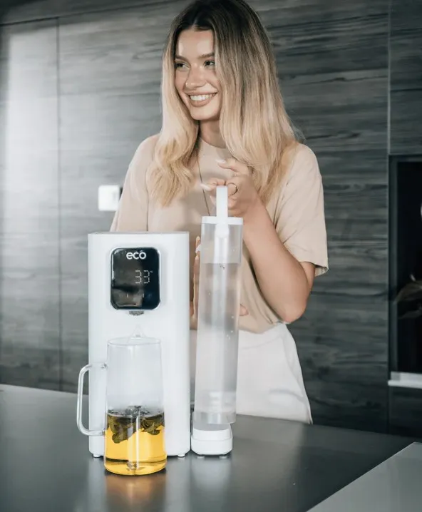 Egy fiatal nő víztisztítót használ a konyhában.