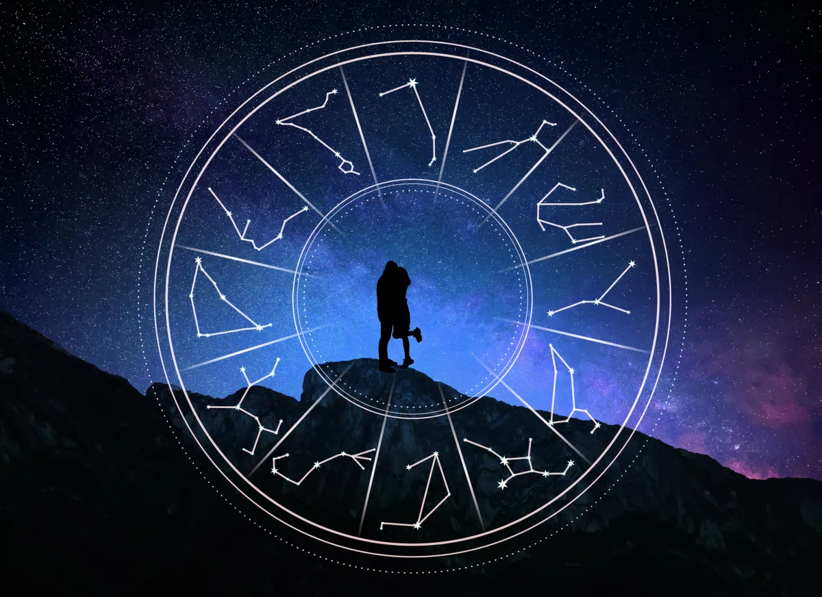 Egy pár ölelkezik a hegyen egy horoszkópban használt zodiákus kör mögött.