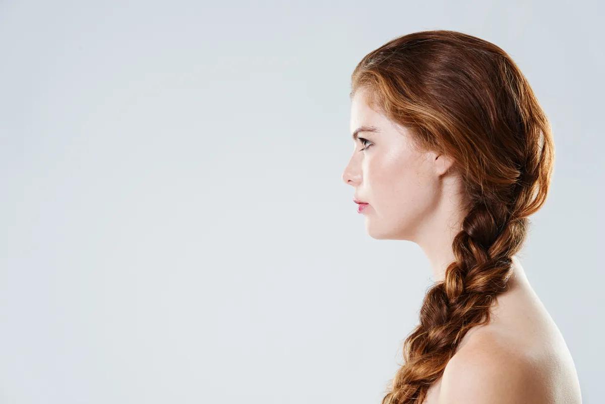 Fiatal vörös hajú nő hagyományos hajfonással profilból