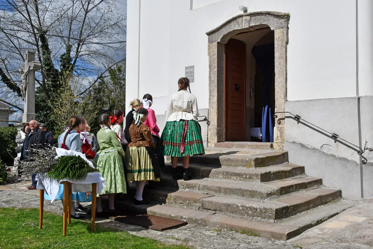 Az ecsédi templom előtt barkaszentelésre készülő népviseletben álló lányok a nagyhéten.