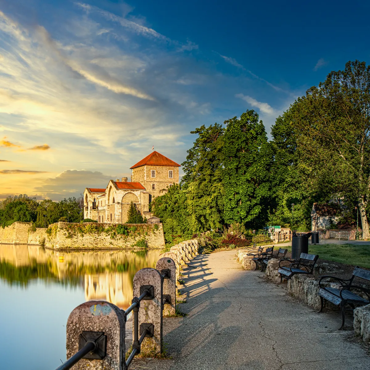 A tatai Öreg-tó partján magasodó tatai vár, és az odavezető sétaút egy nyári napon.