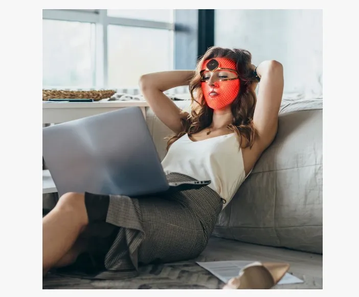 Egy nő ránctalanító készüléket visel az arcán a kanapén fekve.