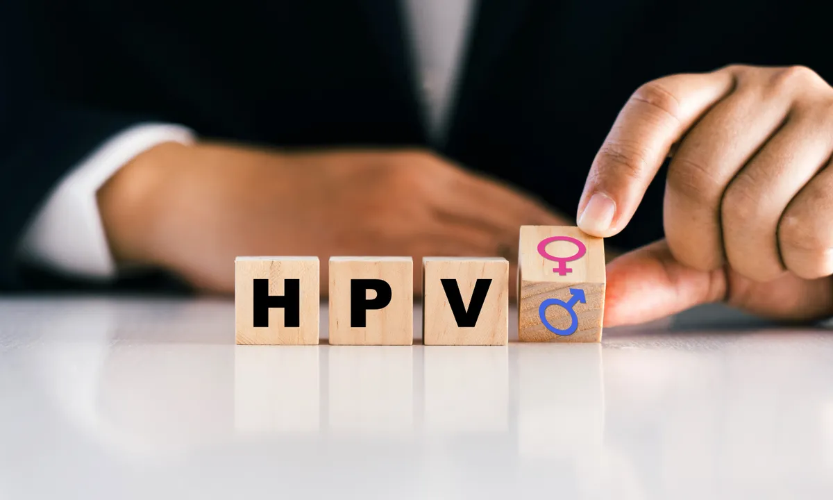 A HPV tüneteire felhívó fakockákat forgató öltönyös férfi.