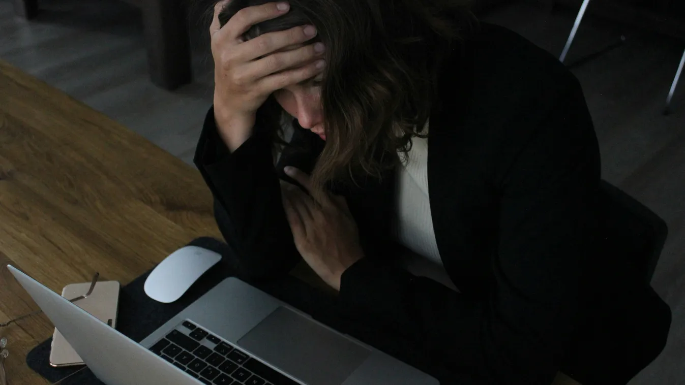 Stresszoldás egy módszerét végző ideges fiatal nő a laptopja előtt görnyedve