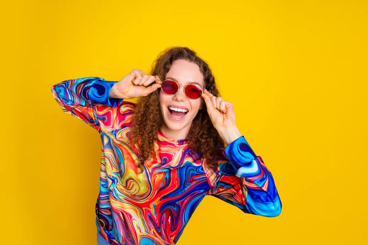 Egy fiatal, boldog nő napszemüvegben a személyiségtesztben.