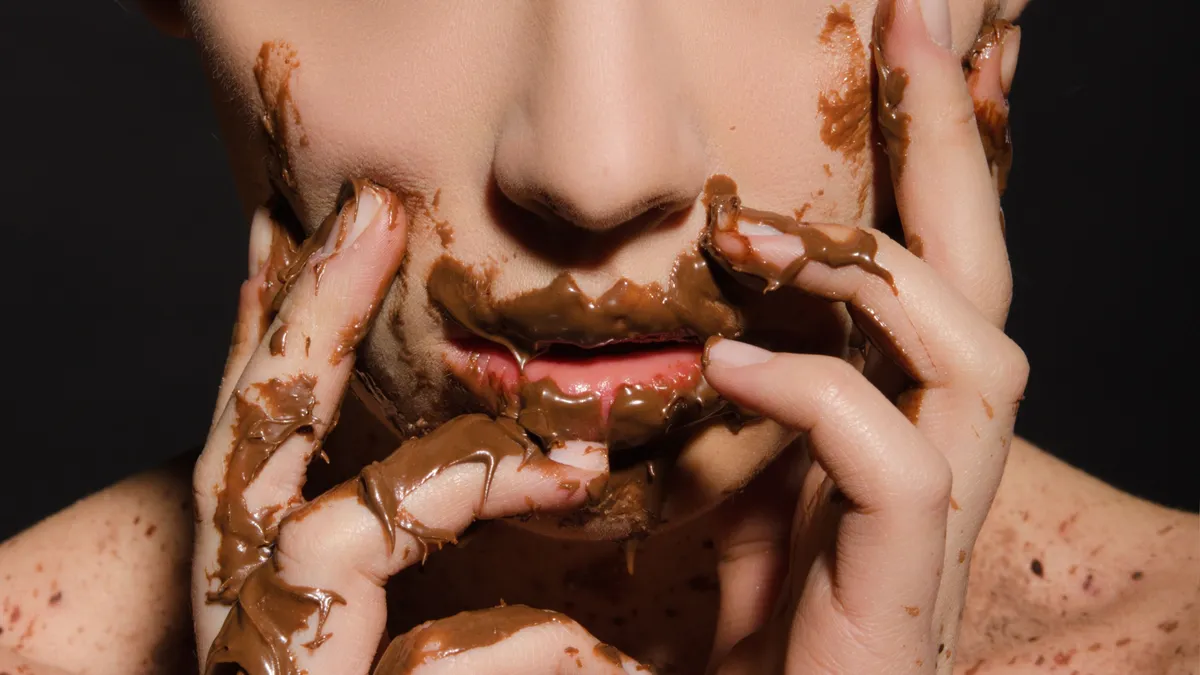 Csokoládéval összekent arca egy nőnek, aki nincs tisztában a csokoládéfogyasztás veszélyeivel