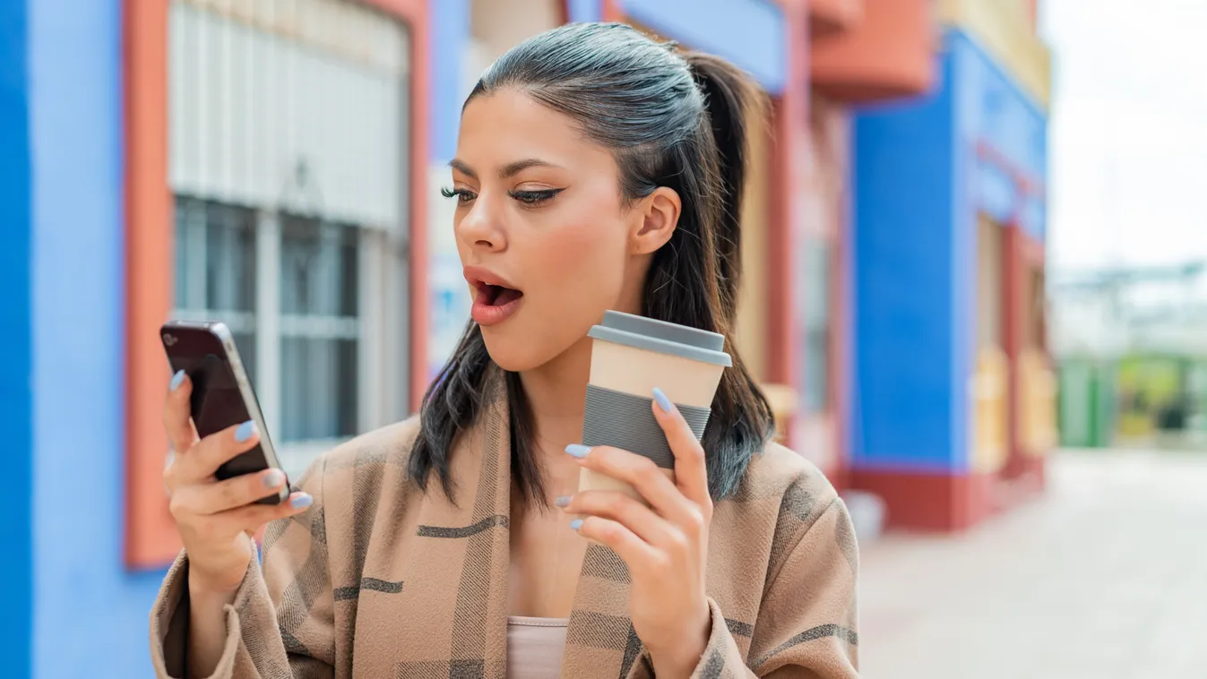 Fiatal nő meglepődve nézi a telefonján a személyiségteszt eredményét.