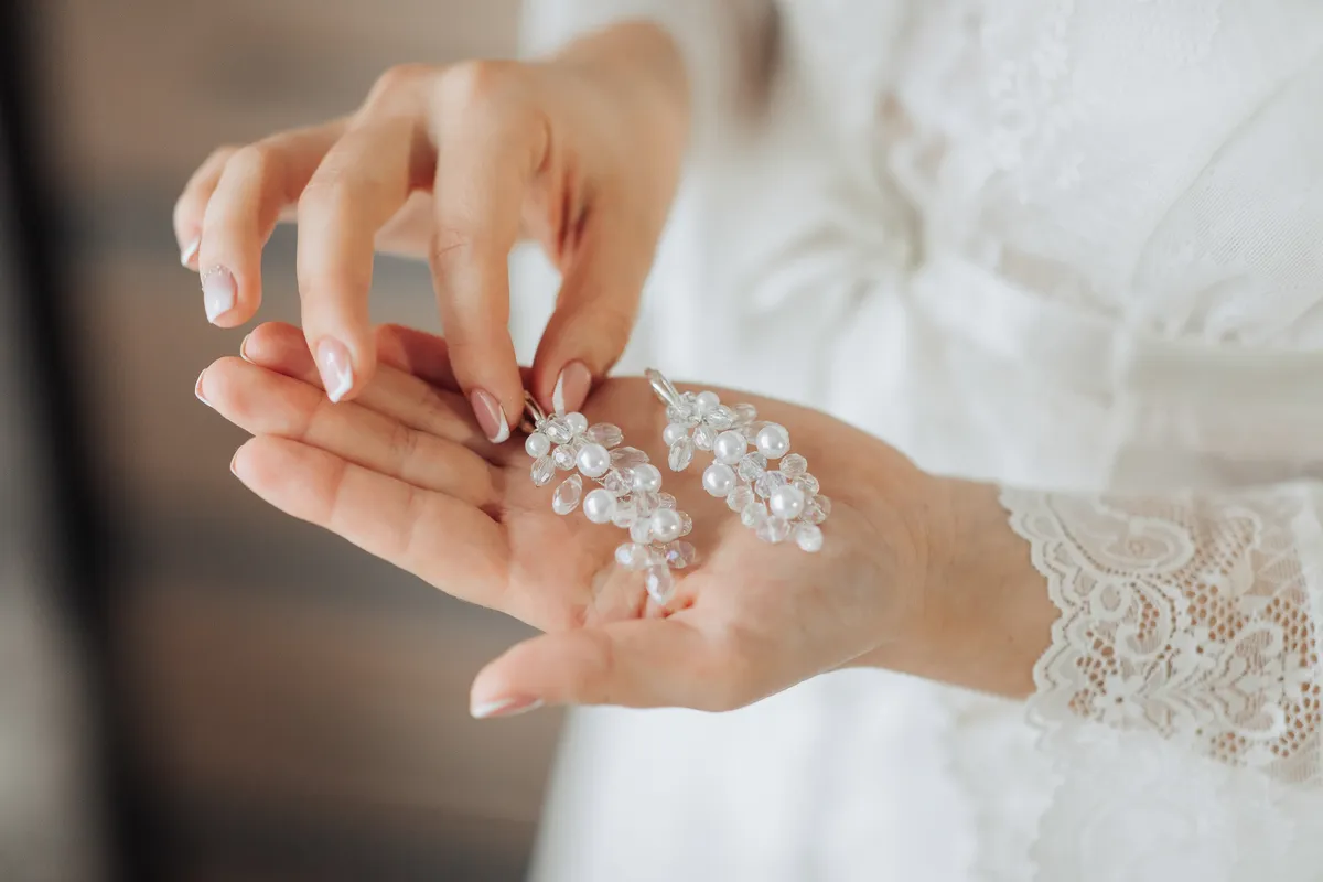 Apró esküvői dekorációk egy menyasszony tenyerében.
