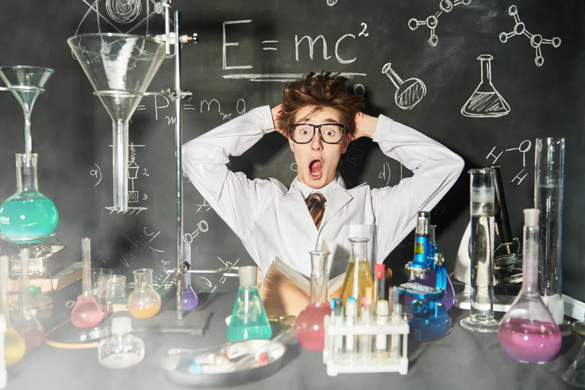 Egy szemüveges vegyész a tábla előtt a kémia kvízben.