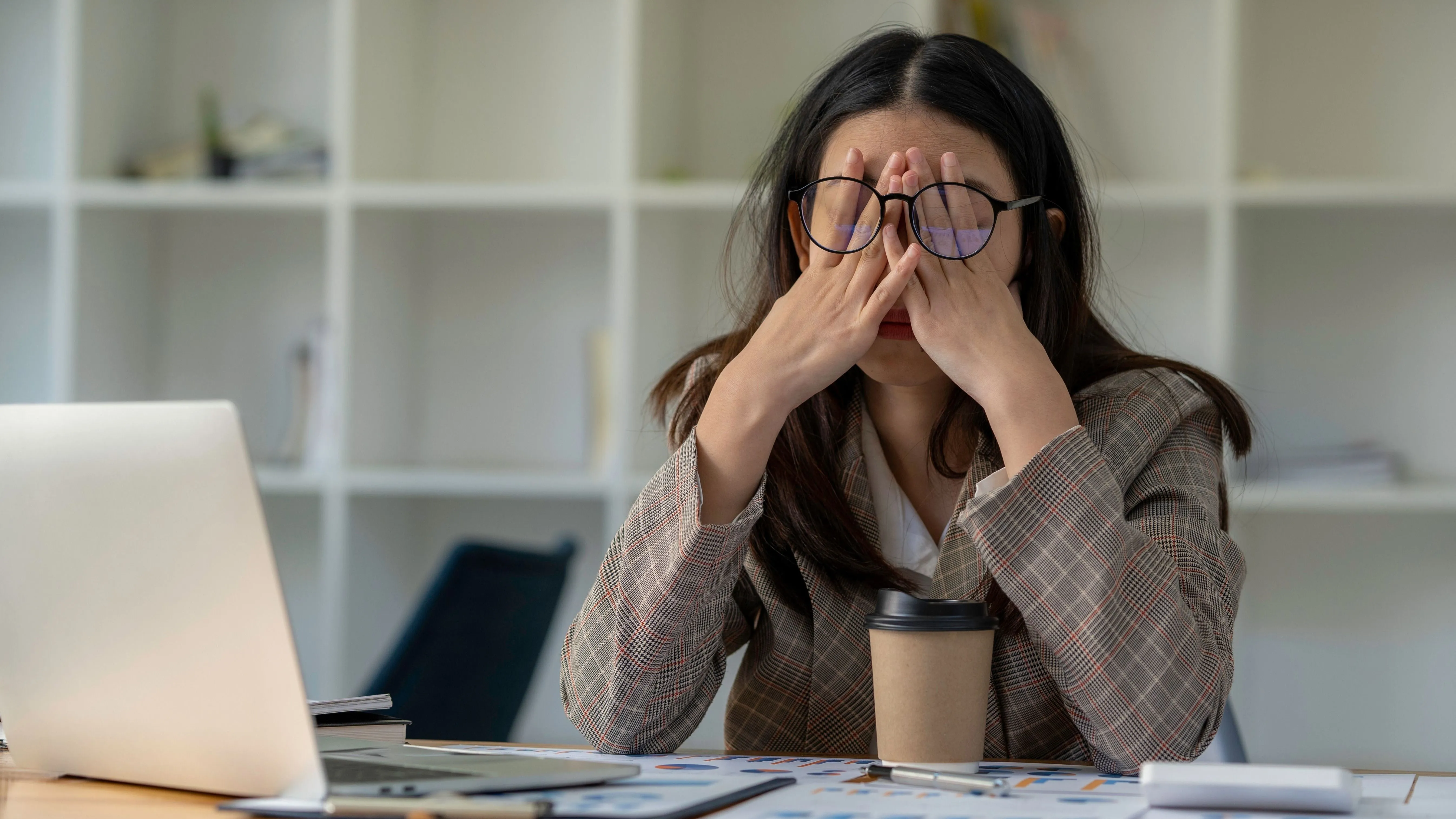 Fiatal nő gyakorolja az idegnyugtatási módszereket a laptopja mögött stresszes helyzetben