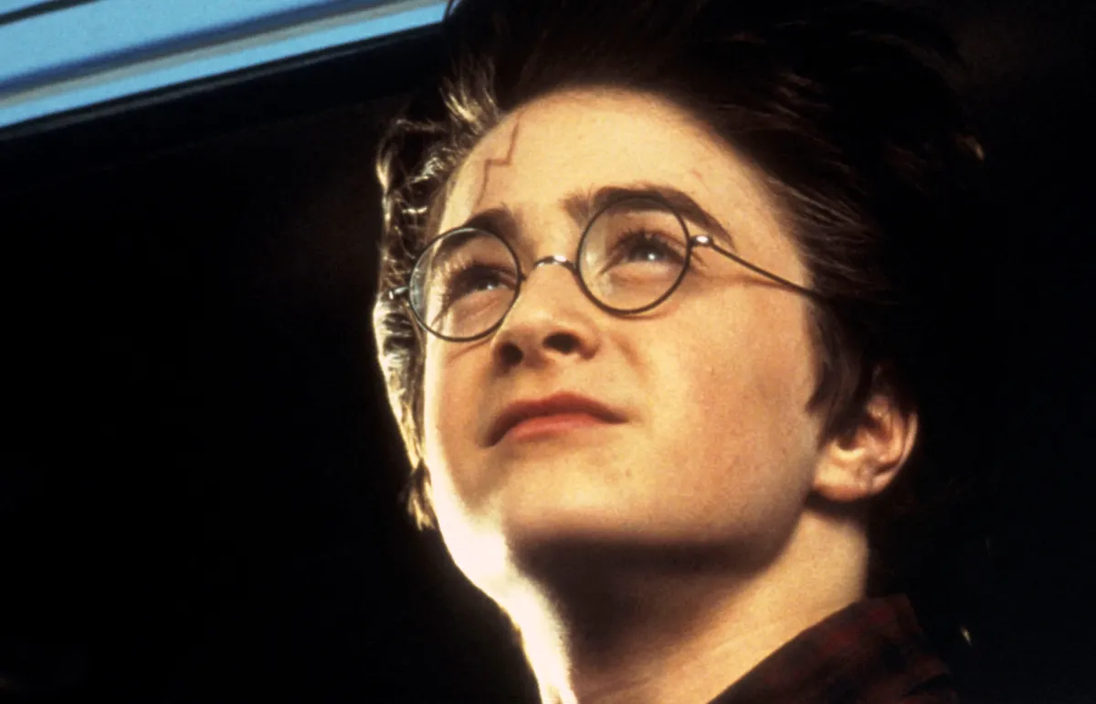 Harry Potter felfelé néz egy irányba, látszik a villám alakú sebhelye.