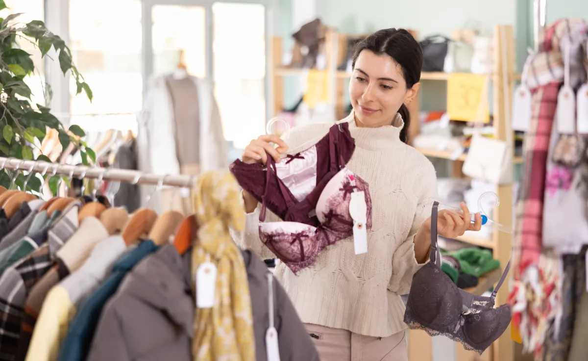 Fiatal nő turizás közben egy melltartót a kezében tartva