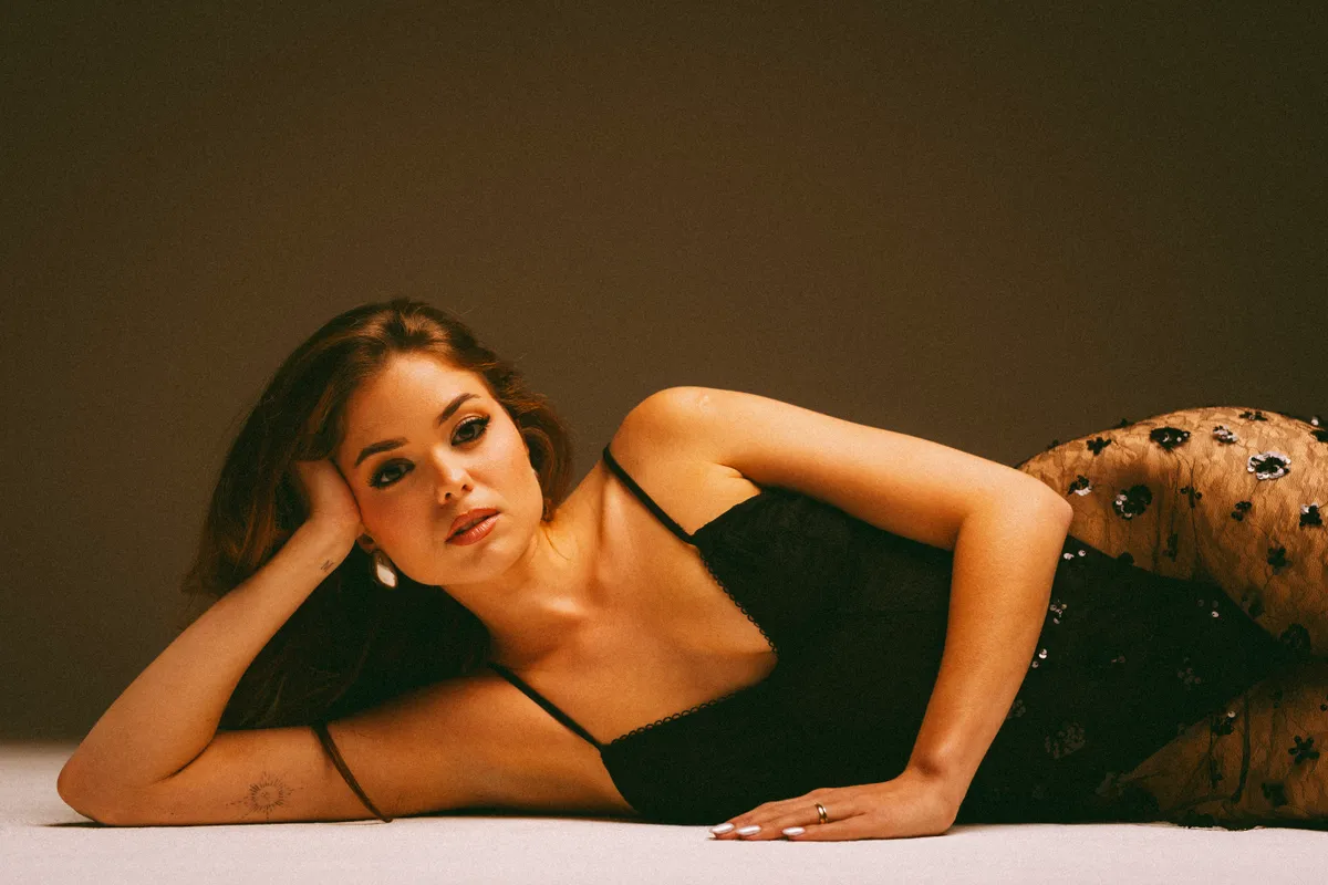 Nagy Bogi egy fekete csipkés ruhában áll modellt. 