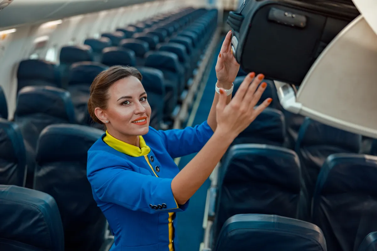 légiutas-kísérő bőröndöt helyez el a felső csomagtárolóban. 