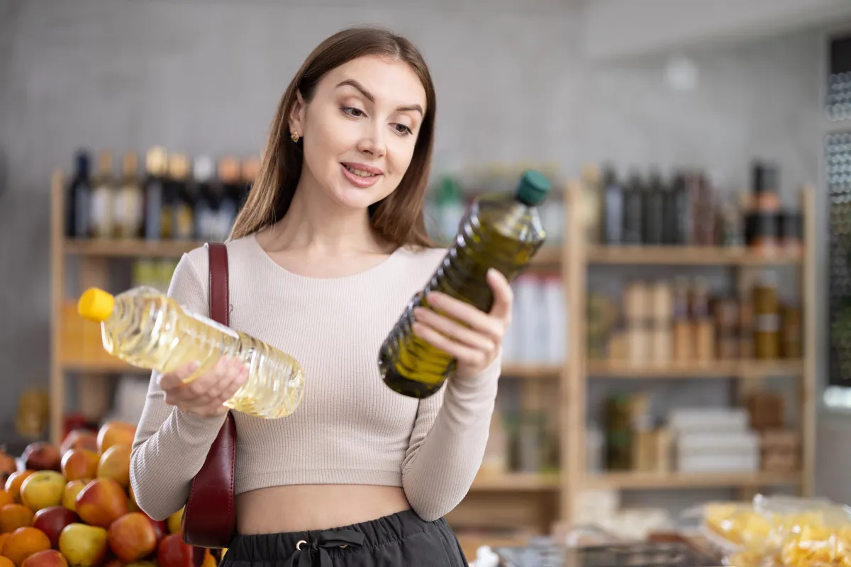 Fiatal nő kétféle olajjal a kezeiben arról gondolkodva, hogy melyik olaj jobb ízületi fájdalom ellen