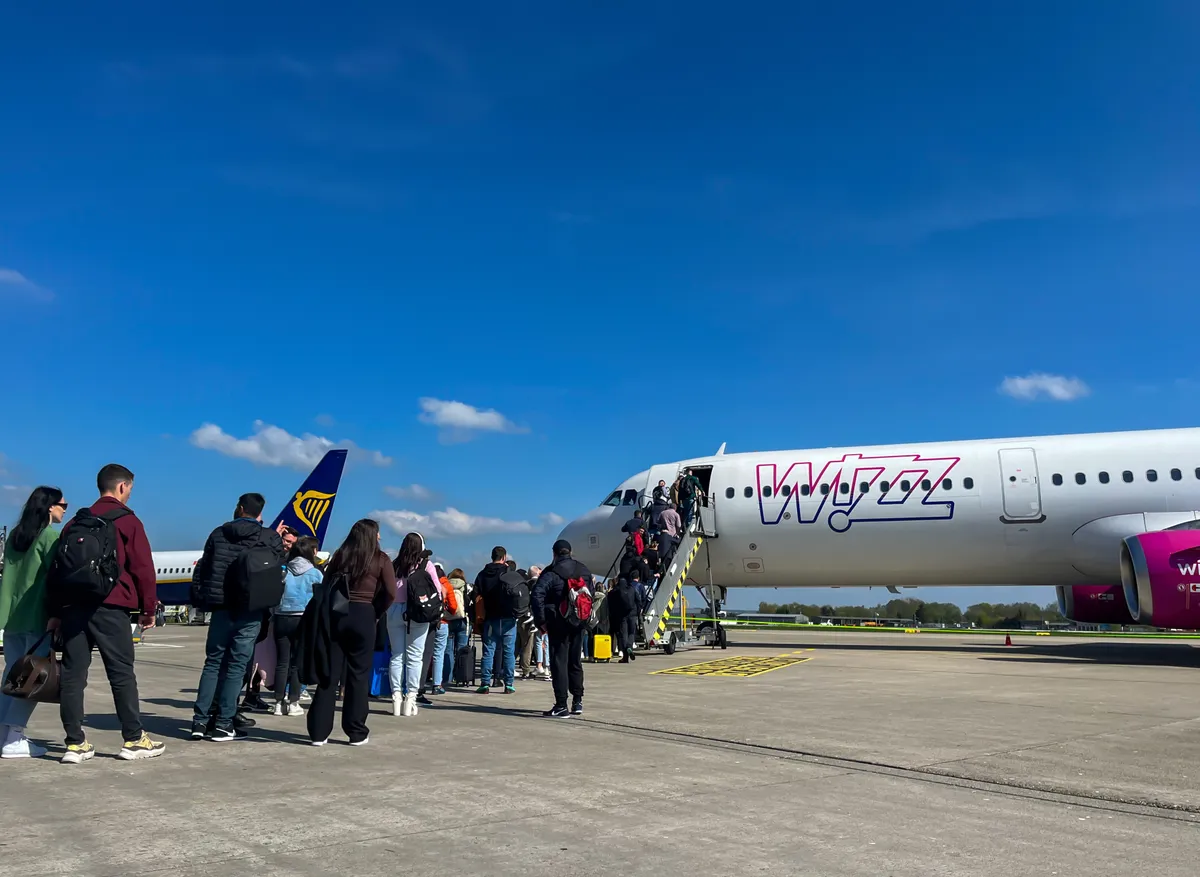 Wizz Air járatra felszálló utasok, a háttérben egy Ryanair gép látható.