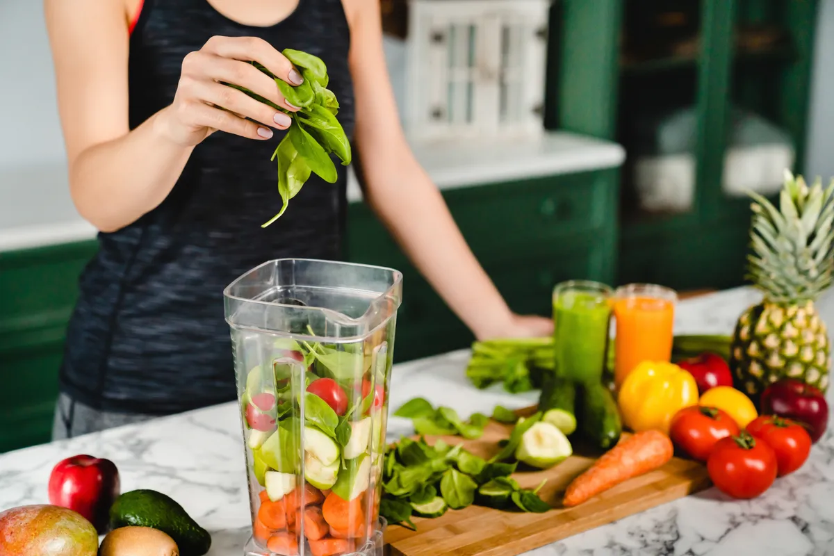 Fiatal lány friss zöldségekből készült zöld detoxkoktélt készít a vércsoportdiéta szerint.