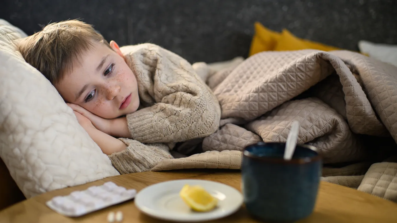 Gyerekbetegségek kvíz, egy beteg kisgyerek fekszik a kanapén.
