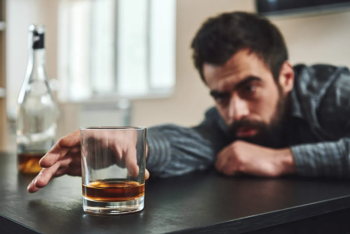 Egy pohár ital után nyúló, alkoholfüggőséggel küzdő férfi