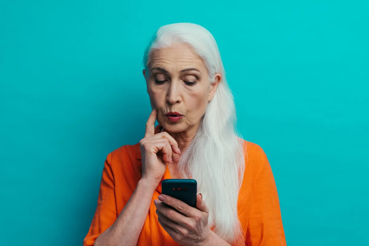 A telefonján kvízt kitöltő idős nő.