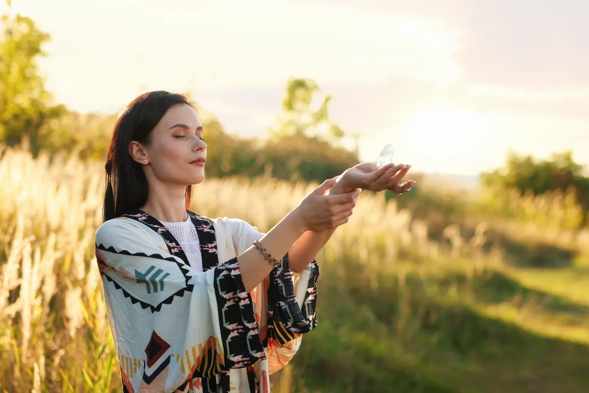 Egy nő a mezőn egy kristállyal meditál a személyiségtesztben.